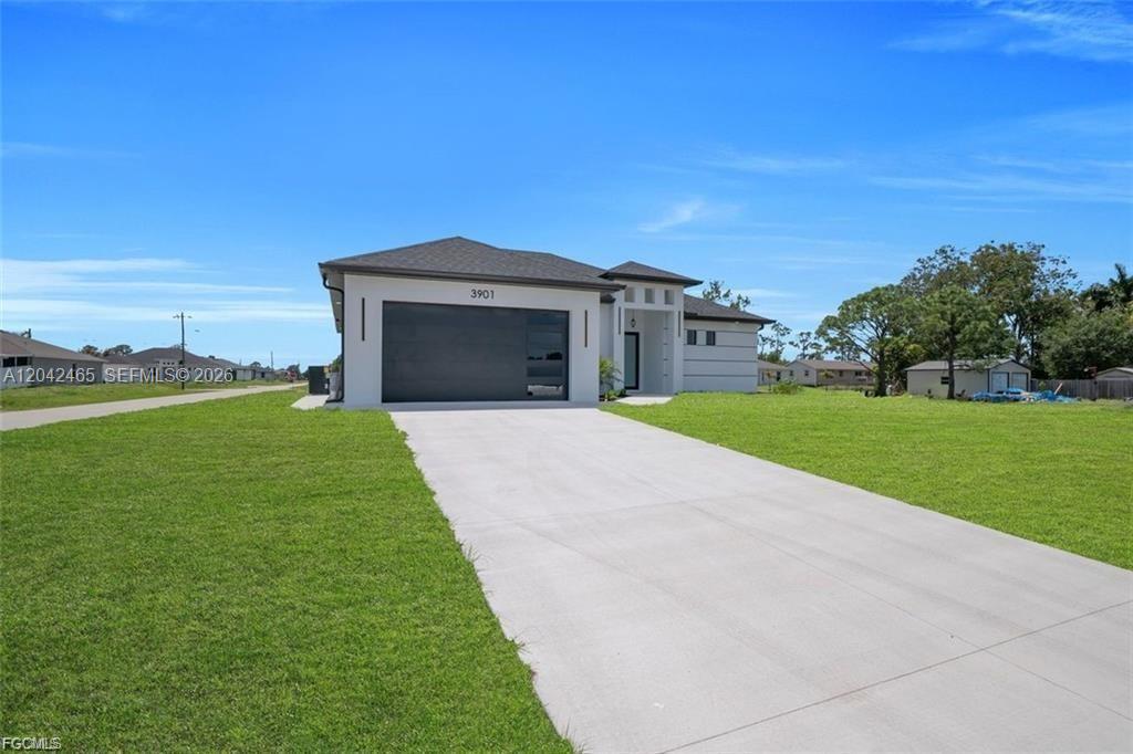 A single-story house with a dark garage door and a concrete driveway sits on grass — 3901 3rd ST SW, Lehigh Acres FL 33976, LEHIGH ACRES, FL