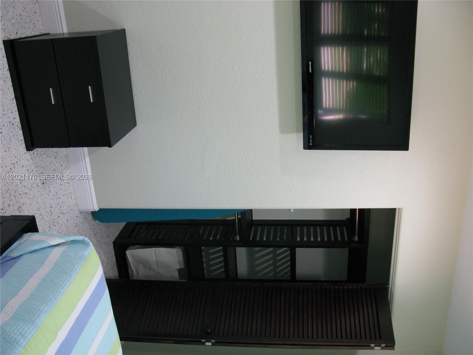 A room features a wall-mounted television, a dark cabinet, and a slatted storage unit — 13767 Oleander Ave, Juno Beach FL 33408, JUNO BEACH, FL
