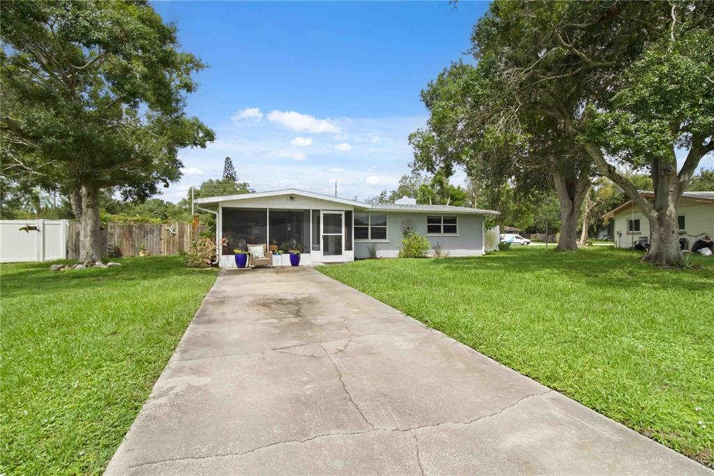 A single-story house with a screened front porch and a concrete driveway sits on a lawn — 535 CARUSO PLACE, SARASOTA, FL