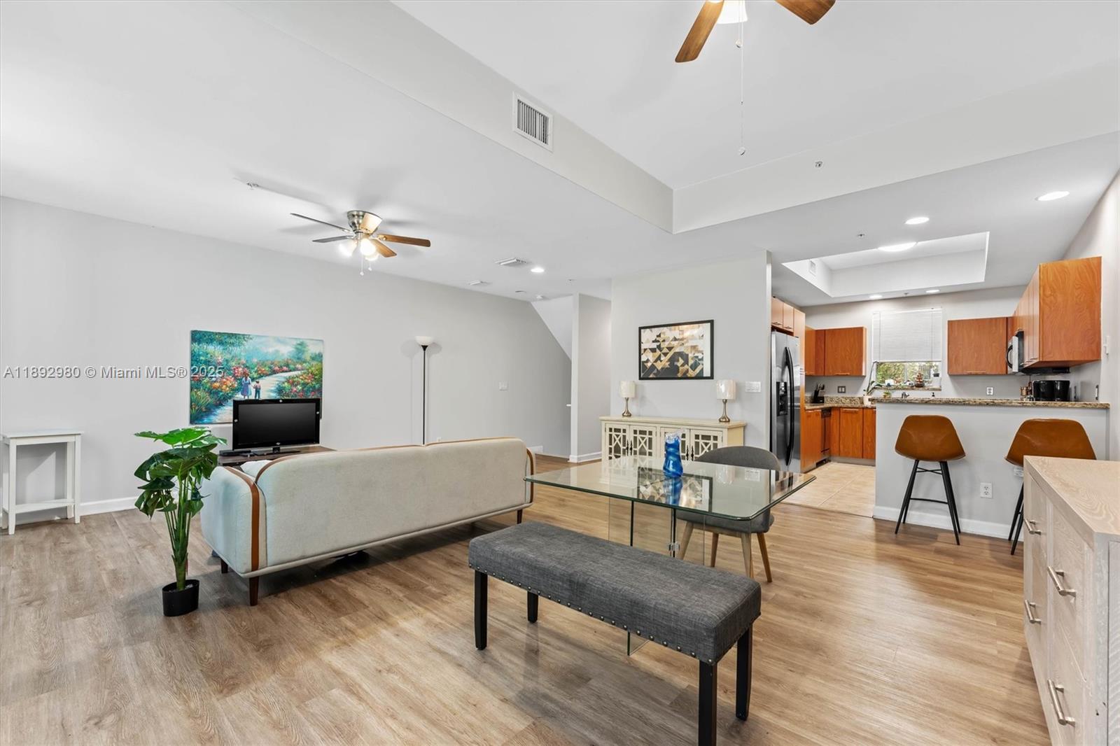 An open-concept living and dining area features light wood flooring and a kitchen with cabinets — 2344 Vintage Dr, Lighthouse Point FL 33064, LIGHTHOUSE POINT, FL
