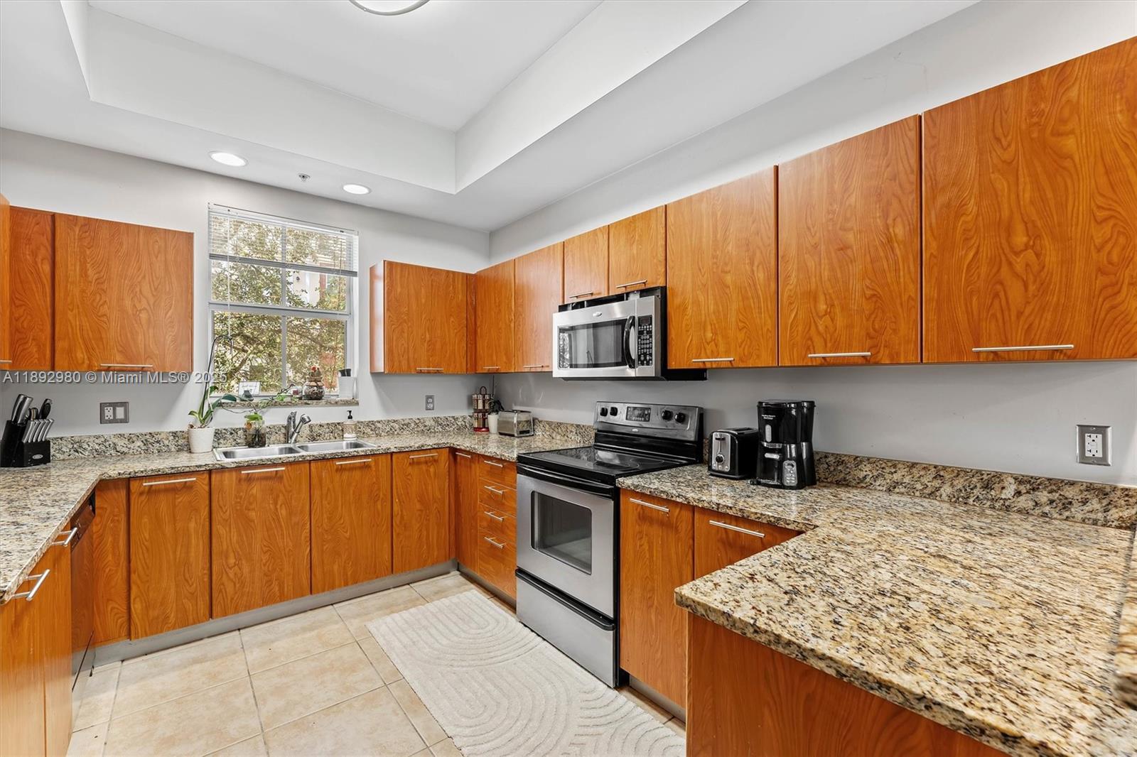 A kitchen features wood cabinets, granite countertops, stainless steel appliances, and a window above the sink — 2344 Vintage Dr, Lighthouse Point FL 33064, LIGHTHOUSE POINT, FL