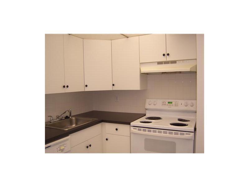 A kitchen featuring white cabinets, dark countertops, a stainless steel sink, and a white stove — 4158 Inverrary Drive # 404, Lauderhill FL 33319, LAUDERHILL, FL