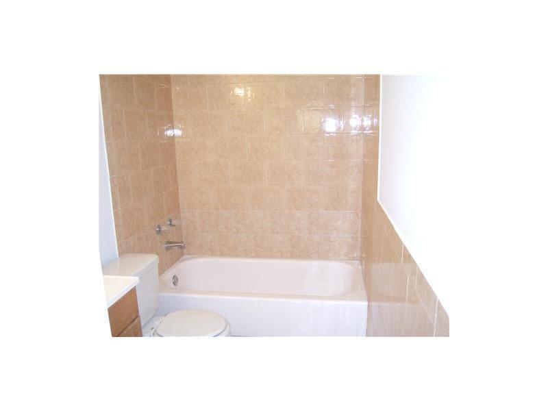 A bathroom with a white bathtub, a toilet, and tan tiled walls — 4158 Inverrary Drive # 404, Lauderhill FL 33319, LAUDERHILL, FL