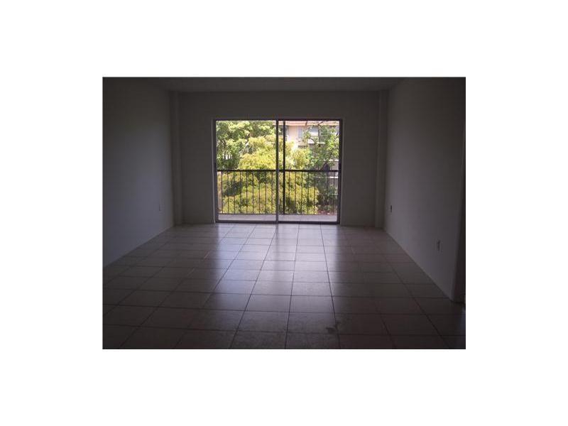 An empty room with light-colored tile flooring and a sliding glass door leading to a balcony — 4158 Inverrary Drive # 404, Lauderhill FL 33319, LAUDERHILL, FL