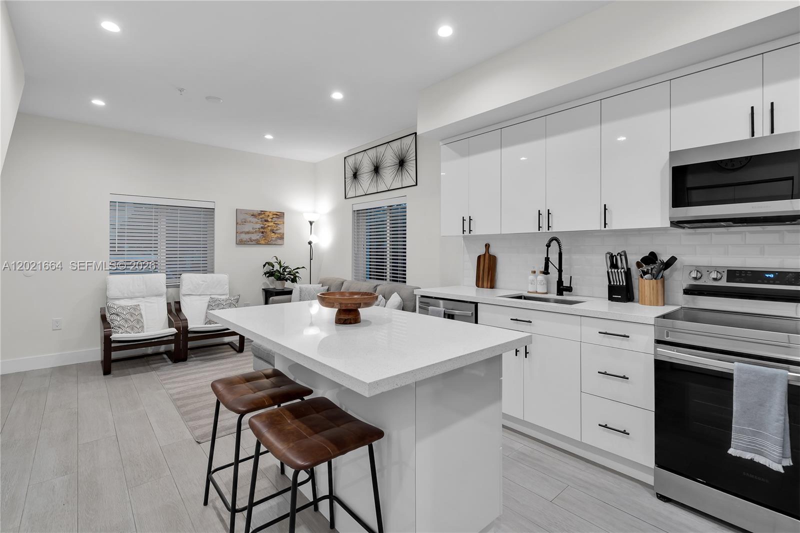 A modern kitchen with white cabinets and a central island overlooks a living area — 1786 SW 9th St # 1, Miami FL 33135, MIAMI, FL