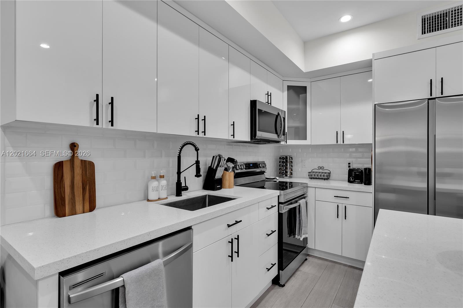 A modern kitchen features white cabinets, stainless steel appliances, and white quartz countertops — 1786 SW 9th St # 1, Miami FL 33135, MIAMI, FL