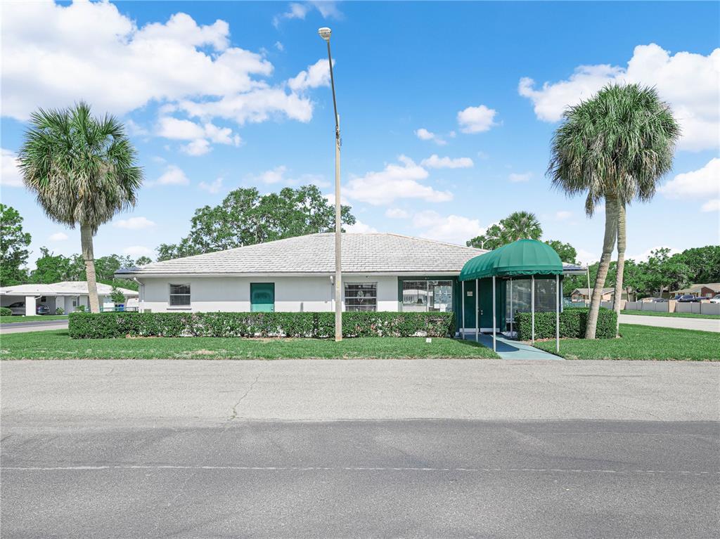 A single-story building with a green awning and two palm trees stands near a road — 601 IMPERIAL BOULEVARD, LAKELAND, FL