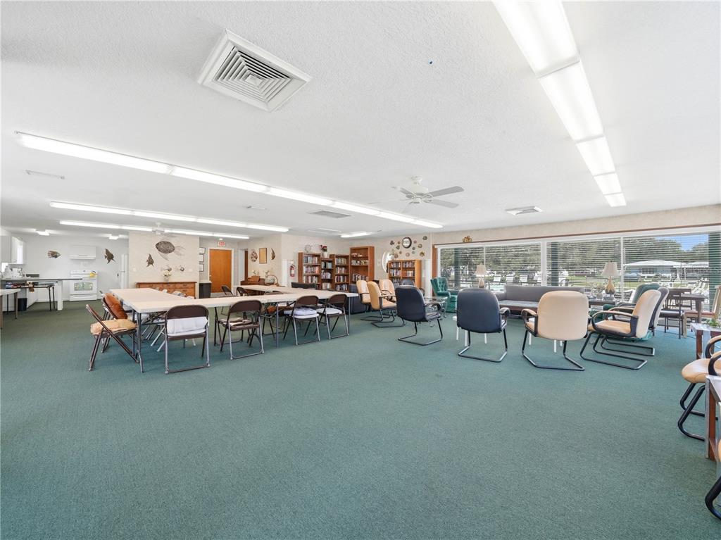 A large community room features green carpeting, rows of chairs, tables, and floor-to-ceiling windows — 601 IMPERIAL BOULEVARD, LAKELAND, FL