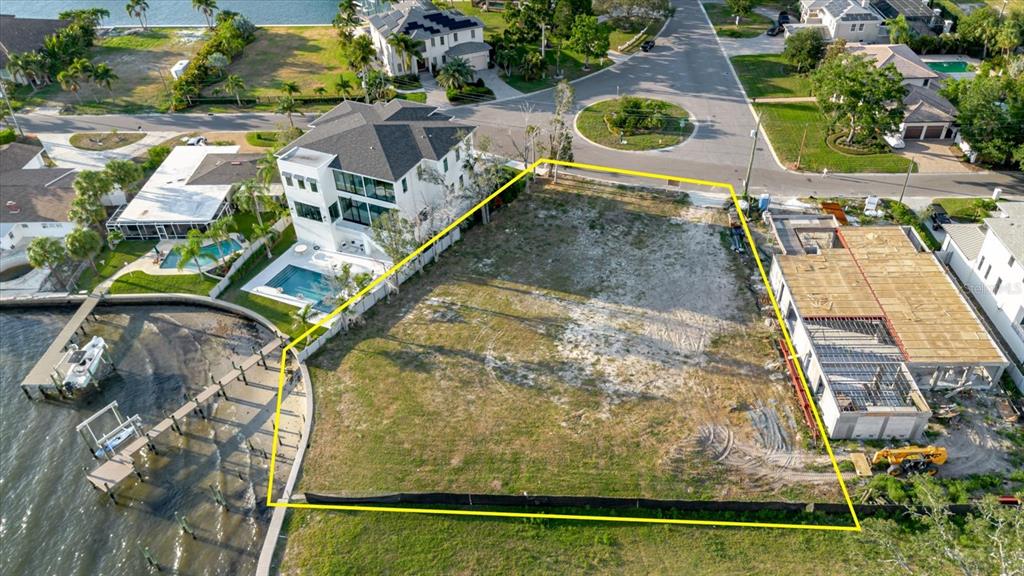 An aerial view shows a vacant waterfront lot outlined in yellow between two houses — 5102 W LONGFELLOW AVENUE, TAMPA, FL