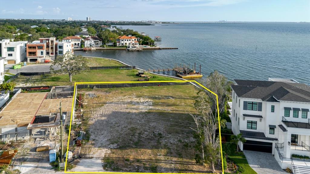 An aerial view shows a vacant waterfront lot outlined in yellow next to residential buildings — 5102 W LONGFELLOW AVENUE, TAMPA, FL
