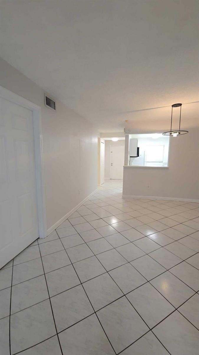 A view of an interior hallway and dining area featuring white tile flooring — 4111 Stirling Road # 406, Dania Beach FL 33314, DANIA BEACH, FL