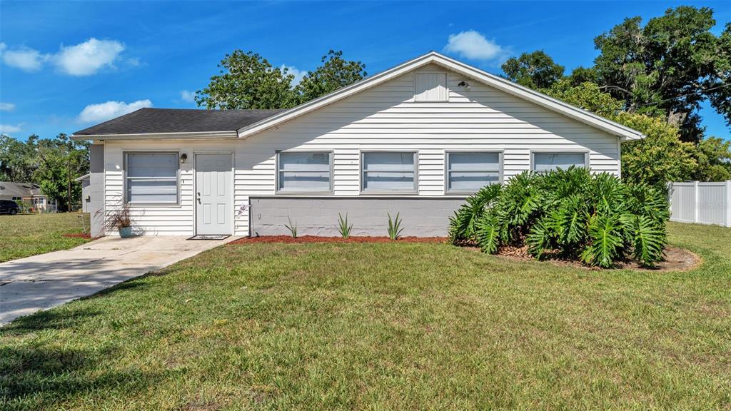 A single-story white house with a gray base and a front lawn under a blue sky — 5353 7TH STREET SE, LAKELAND, FL