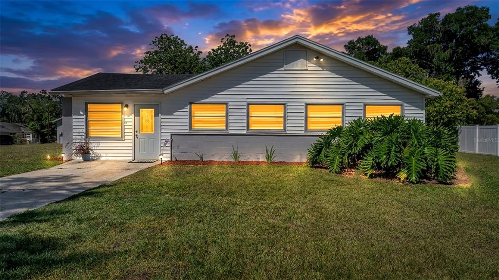 A single-story house with white siding and a large front lawn at sunset — 5353 7TH STREET SE, LAKELAND, FL