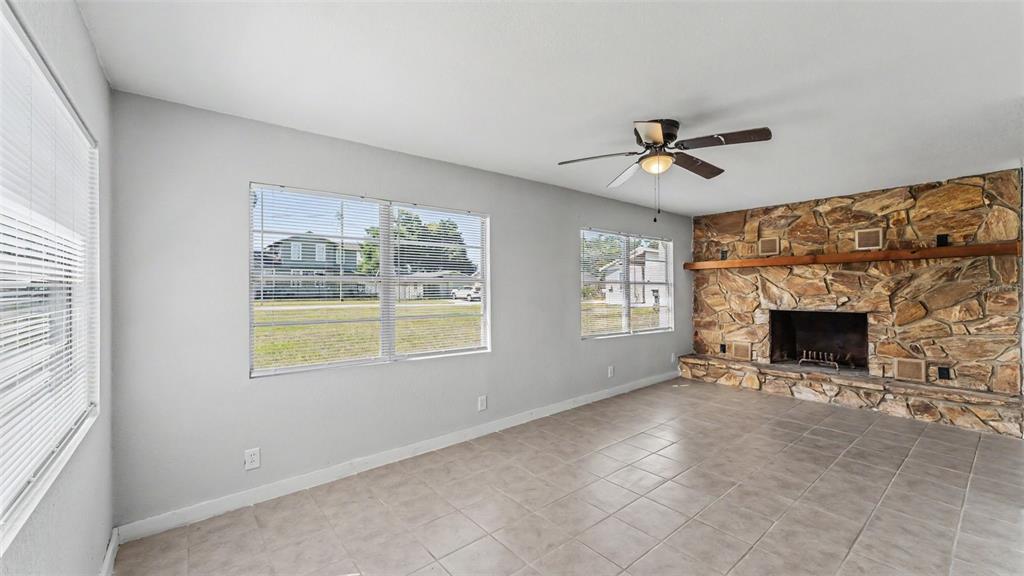 A living room features light gray walls, tile flooring, a ceiling fan, and a stone fireplace — 5353 7TH STREET SE, LAKELAND, FL