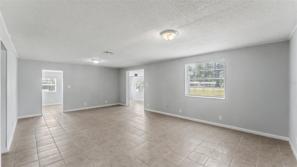 An open living area features light gray walls, tan tile flooring, and two ceiling lights — 5353 7TH STREET SE, LAKELAND, FL