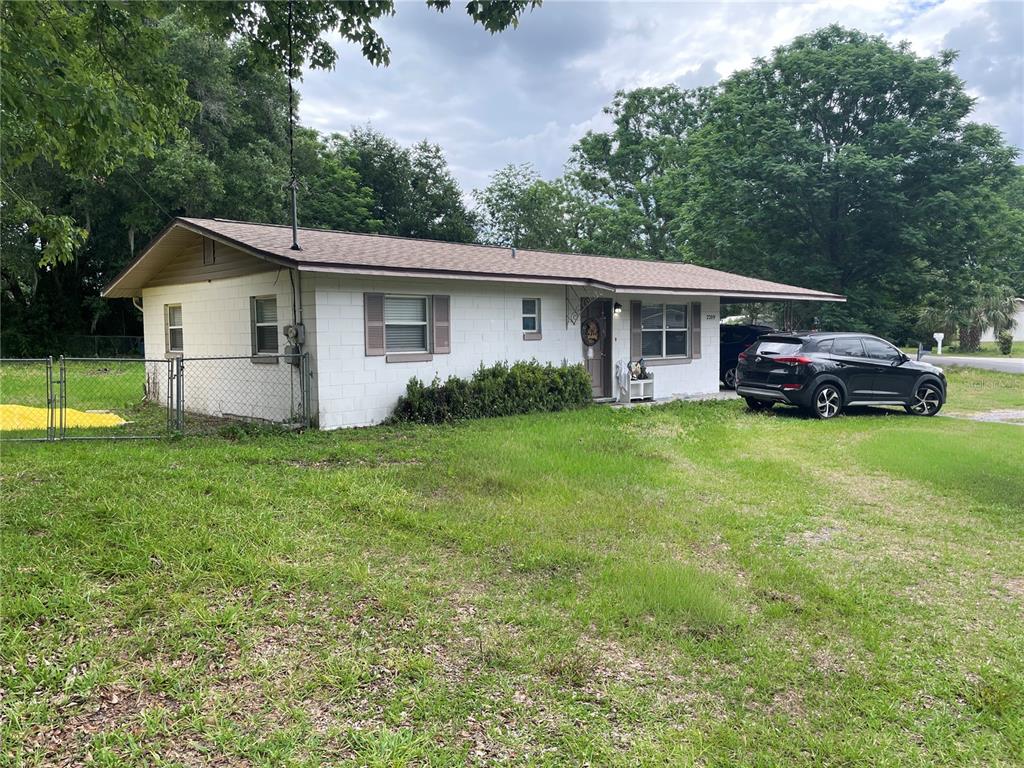 A single-story white concrete block house with a brown roof and an attached carport — 2209 NE 36TH STREET, OCALA, FL