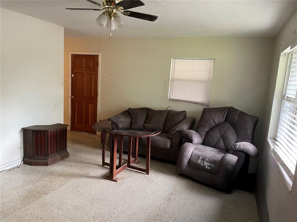 A living room features a ceiling fan, a brown sofa, a recliner, and a wooden table — 2209 NE 36TH STREET, OCALA, FL