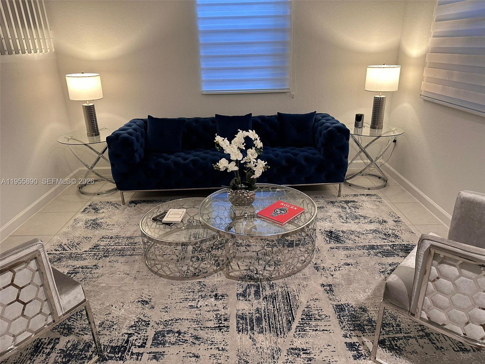 A living room features a blue tufted sofa, two glass coffee tables, and two armchairs — 12961 SW 230th St, Miami FL 33170, MIAMI, FL
