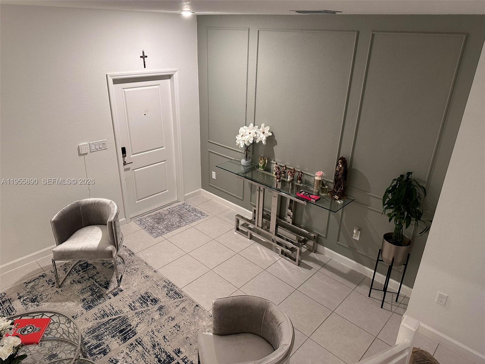 An entryway features a glass console table, gray paneled walls, and two velvet armchairs — 12961 SW 230th St, Miami FL 33170, MIAMI, FL