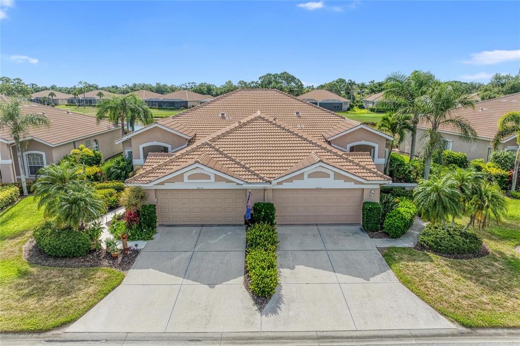 An aerial view of a duplex home with a tiled roof and two-car garages — 9532 FOREST HILLS CIRCLE, SARASOTA, FL