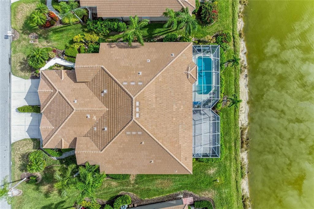 An aerial view shows a house with a tiled roof, pool enclosure, and waterfront backyard — 9532 FOREST HILLS CIRCLE, SARASOTA, FL