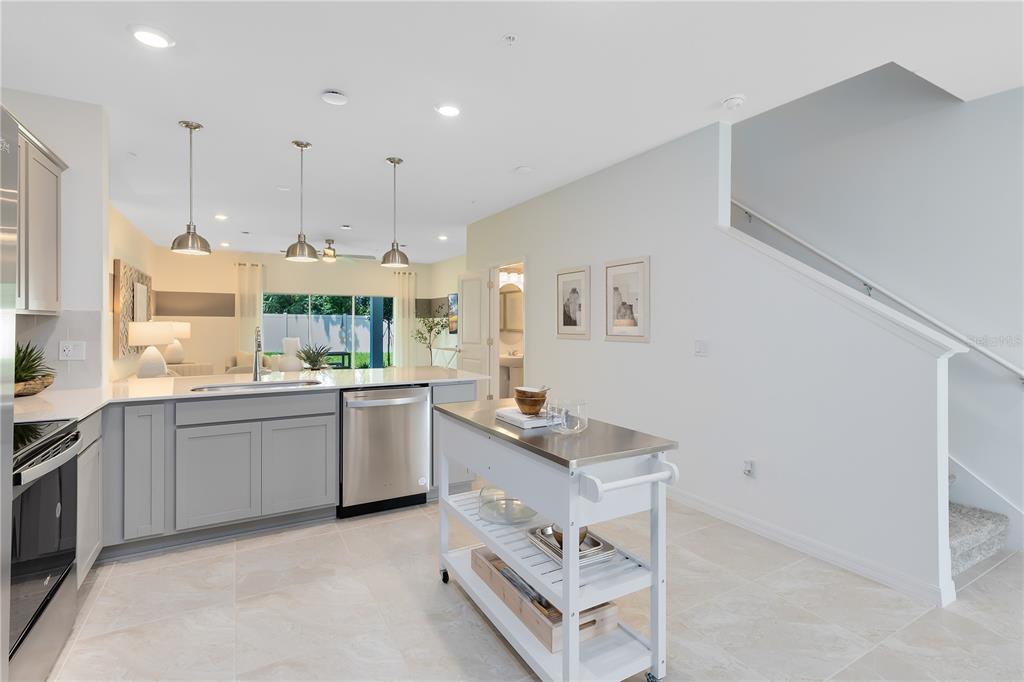 A kitchen with gray cabinets, stainless steel appliances, a rolling island, and an adjacent staircase — 4975 SUNRISE ESTATES DRIVE, WEST MELBOURNE, FL