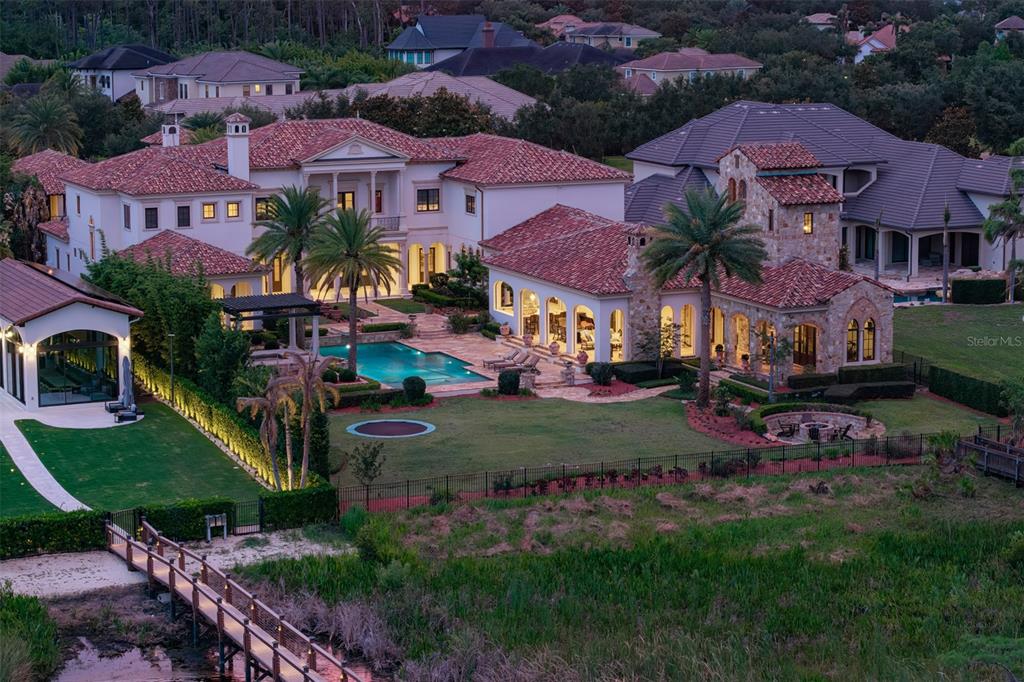 An aerial view of a large Mediterranean-style estate featuring a pool, lawn, and private dock — 6119 GROSVENOR SHORE DRIVE, WINDERMERE, FL