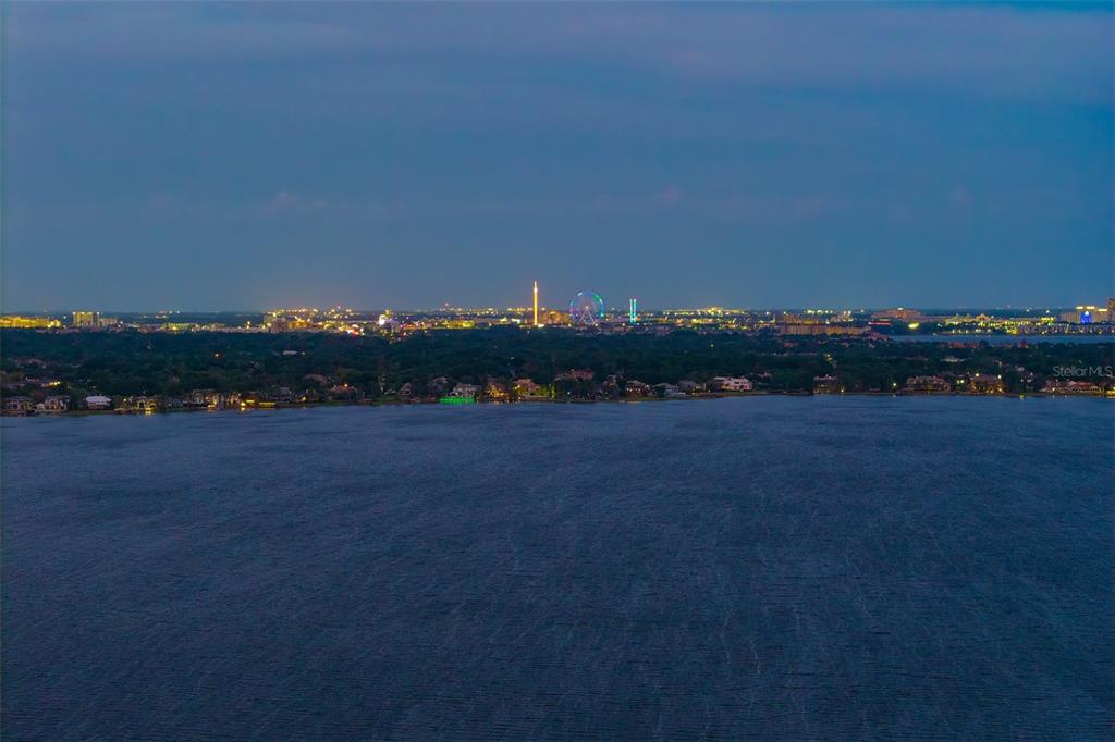 An aerial view of a lake at dusk with a distant city skyline — 6119 GROSVENOR SHORE DRIVE, WINDERMERE, FL