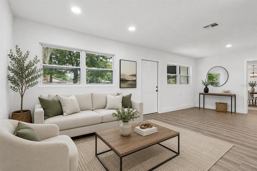A bright living room features a beige sofa, wood coffee table, and light wood flooring — 1207 32ND STREET NW, WINTER HAVEN, FL