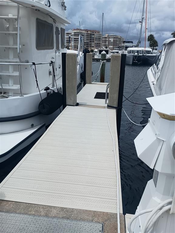 A view of a boat slip with a light-colored dock between two docked boats — 2600 HARBOURSIDE DRIVE UNIT P-05, LONGBOAT KEY, FL