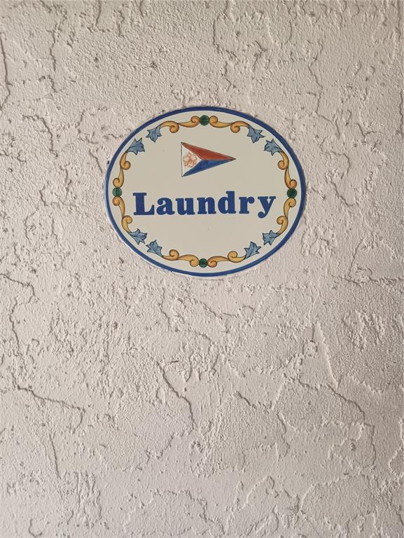 An oval decorative sign labeled Laundry is mounted on a textured, off-white wall — 2600 HARBOURSIDE DRIVE UNIT P-05, LONGBOAT KEY, FL