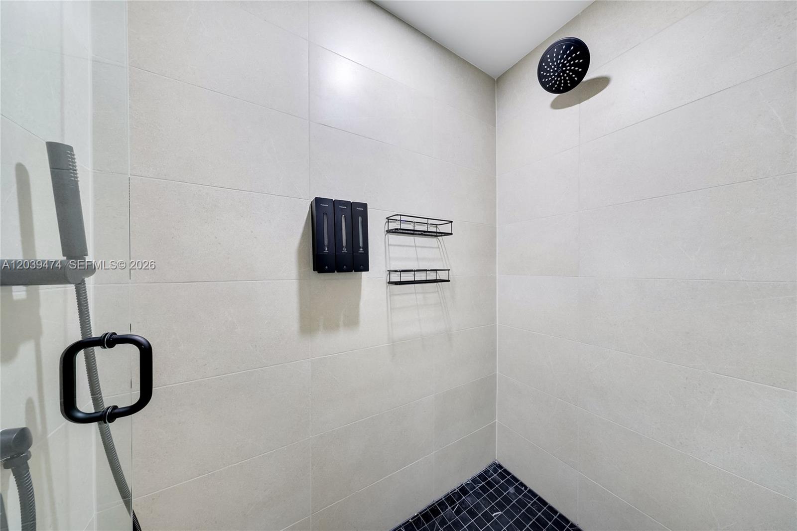 A modern shower features light-colored wall tiles, a black rainfall showerhead, and wall-mounted dispensers — 225 N Miami Ave # 1510, Miami FL 33128, MIAMI, FL