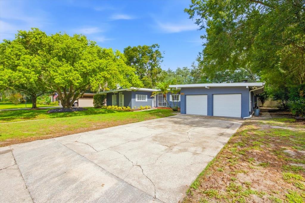 A single-story blue house with a two-car garage and a large concrete driveway — 1626 SIMS PLACE, LAKELAND, FL
