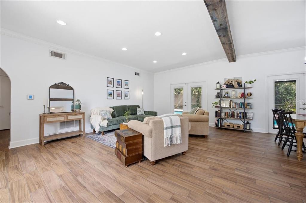A living room features wood-look tile flooring, a dark wood ceiling beam, and a bookshelf — 1626 SIMS PLACE, LAKELAND, FL