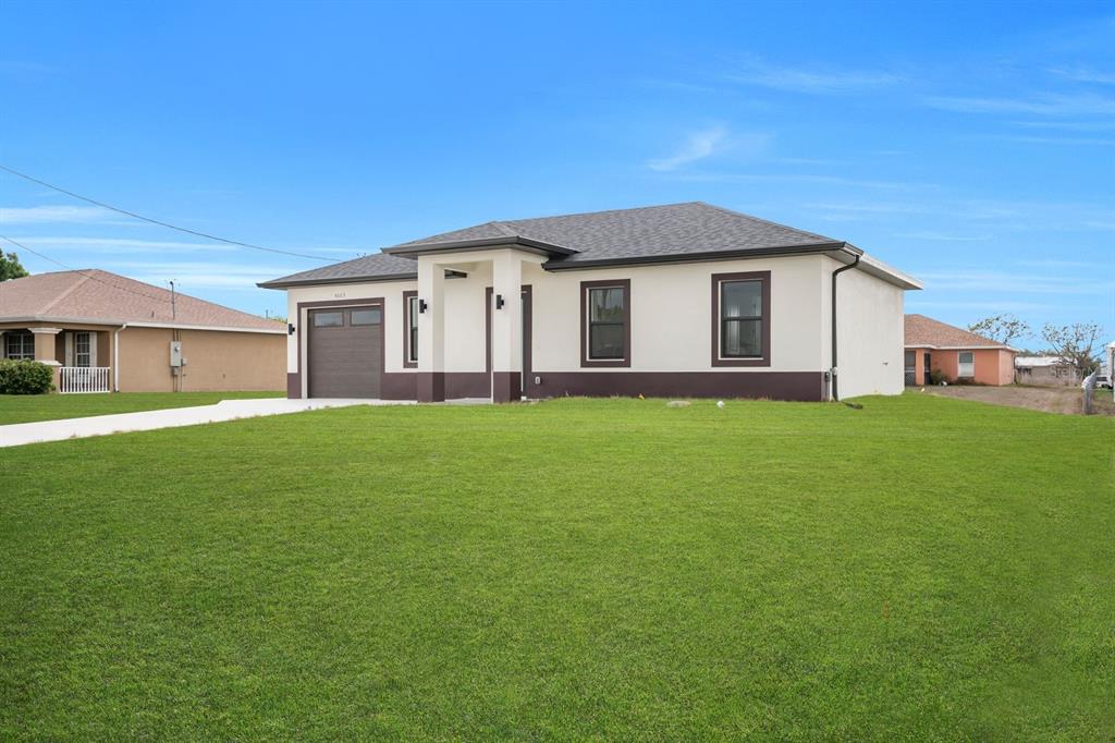 A single-story house with a white and brown exterior, a garage, and a large lawn — 4003 10TH STREET SW, LEHIGH ACRES, FL