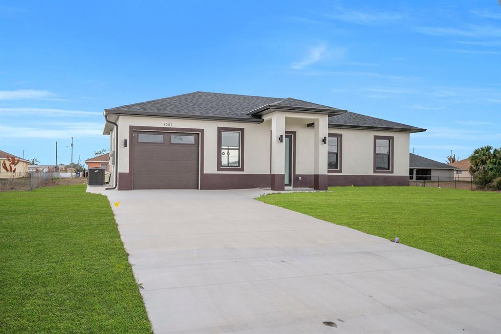 A single-story house with a two-tone exterior, a concrete driveway, and a garage — 4003 10TH STREET SW, LEHIGH ACRES, FL