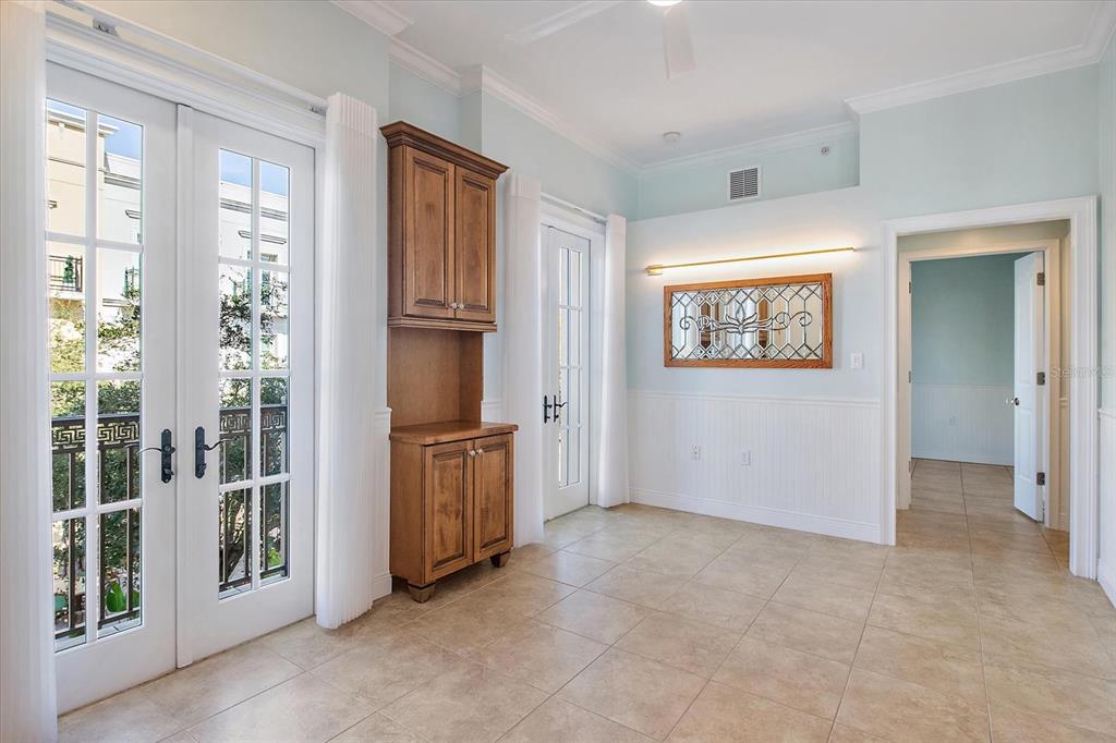 A room with tile floors, a wooden cabinet, French doors, and a decorative wall mirror — 445 N ORANGE AVENUE UNIT 210, SARASOTA, FL