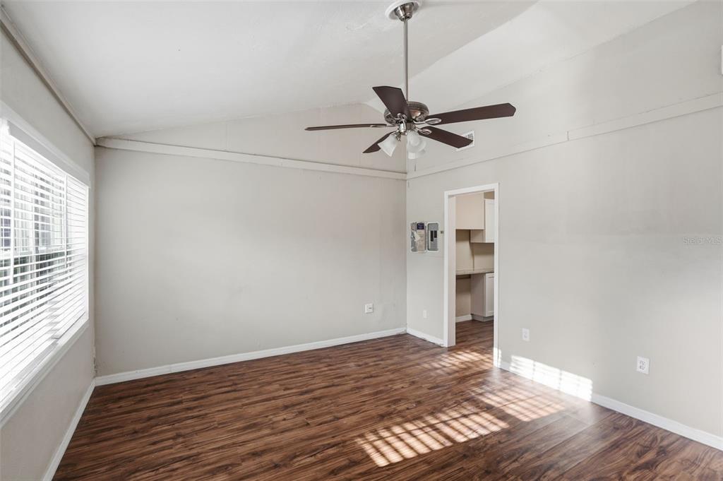 An empty room features wood-look flooring, a vaulted ceiling with a fan, and a doorway — 303 JOSEPHINE AVENUE, FRUITLAND PARK, FL