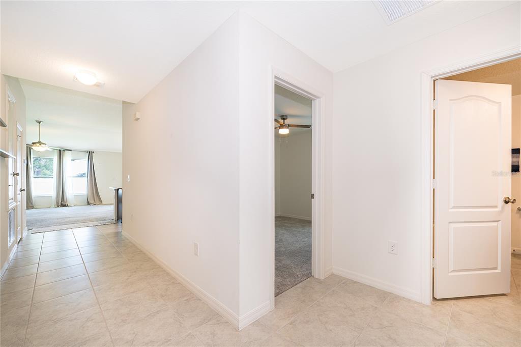 A tiled hallway leads to a carpeted room and an open living area with windows — 2405 BULRUSH DRIVE, ST CLOUD, FL