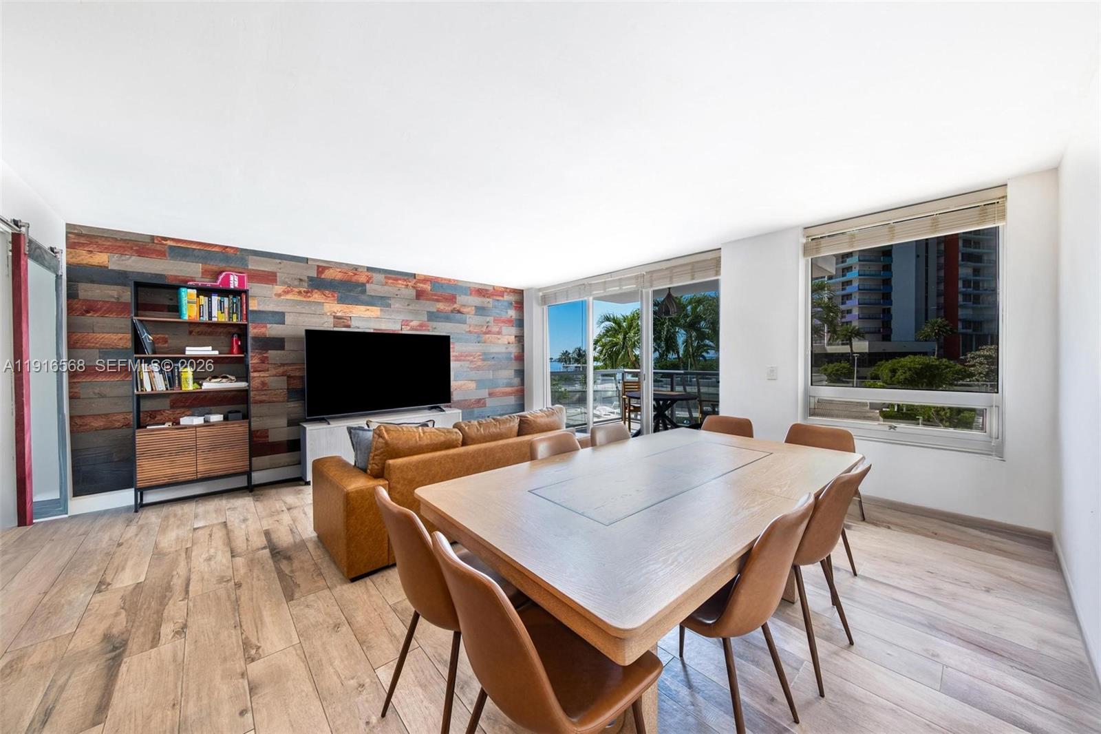 A living and dining area features a wood-paneled accent wall, leather furniture, and balcony views — 1541 Brickell Ave # C406, Miami FL 33129, MIAMI, FL