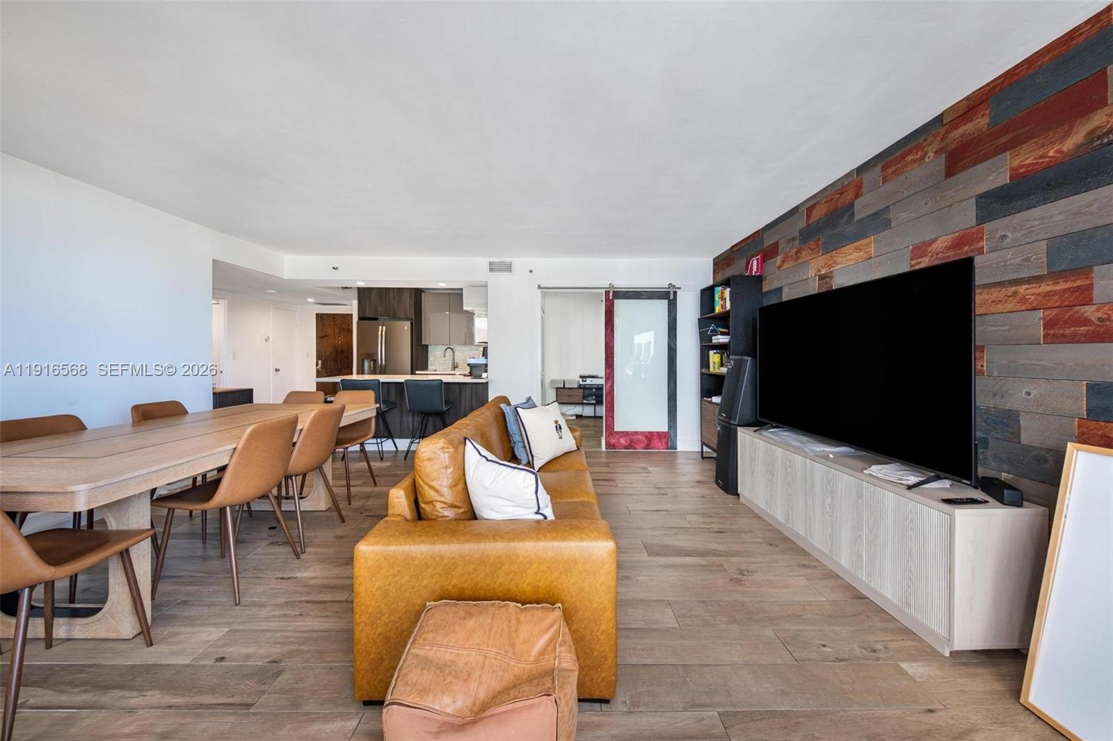 This living and dining area features wood-plank flooring, a rustic accent wall, and leather furniture — 1541 Brickell Ave # C406, Miami FL 33129, MIAMI, FL