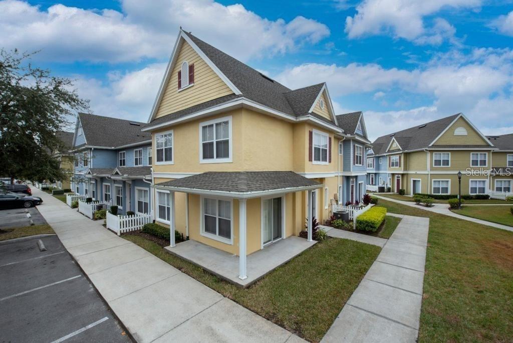 A yellow two-story townhouse with a covered porch and a gray shingled roof — 4012 SANTA MARIA DRIVE UNIT 101, KISSIMMEE, FL