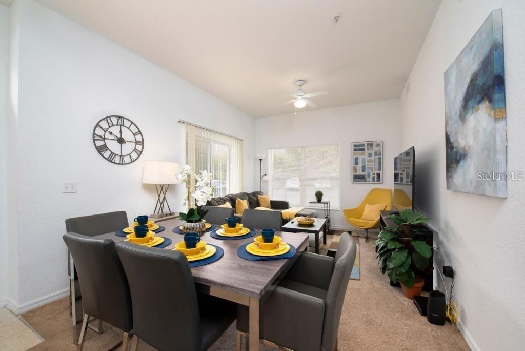 A dining area with a grey table and chairs opens into a living room space — 4012 SANTA MARIA DRIVE UNIT 101, KISSIMMEE, FL