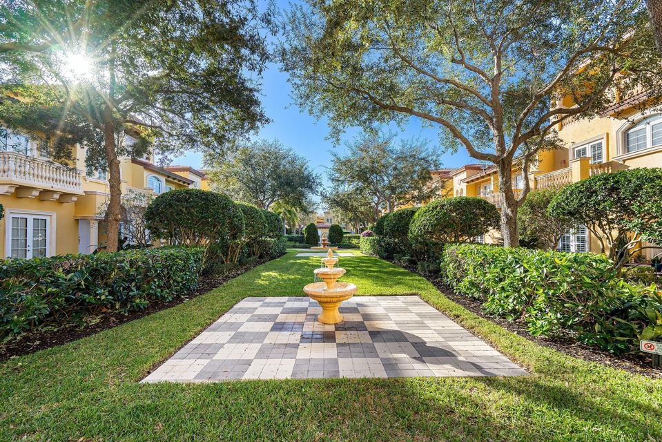 A tiered fountain sits on a checkered patio between two rows of yellow residential buildings — 210 NE 69th Circle, Boca Raton FL 33487, BOCA RATON, FL