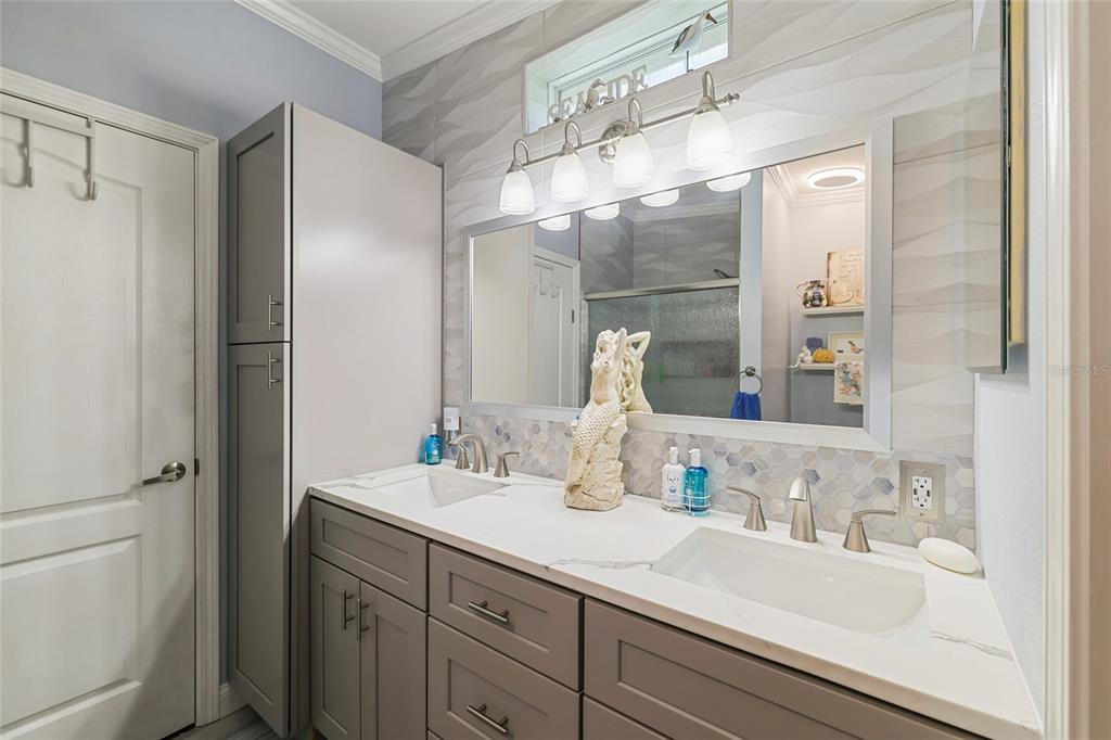 A bathroom features a double vanity with gray cabinets, white countertops, and a large mirror — 24500 RIO VILLA LAKES CIRCLE, PUNTA GORDA, FL