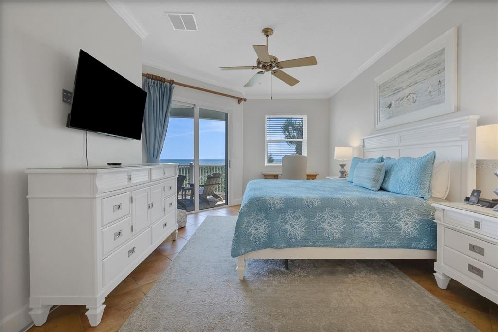 A bedroom with a white dresser, a bed with blue bedding, and a balcony view — 900 CINNAMON BEACH WAY UNIT 822, PALM COAST, FL