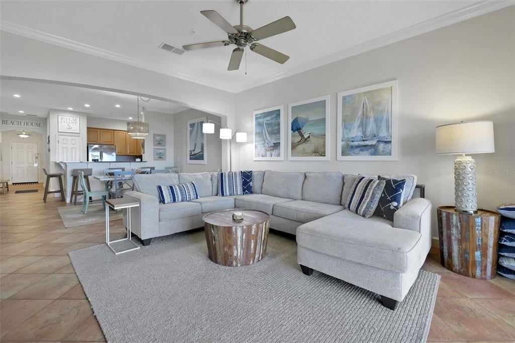A living room features a gray sectional sofa, a round wooden coffee table, and nautical artwork — 900 CINNAMON BEACH WAY UNIT 822, PALM COAST, FL