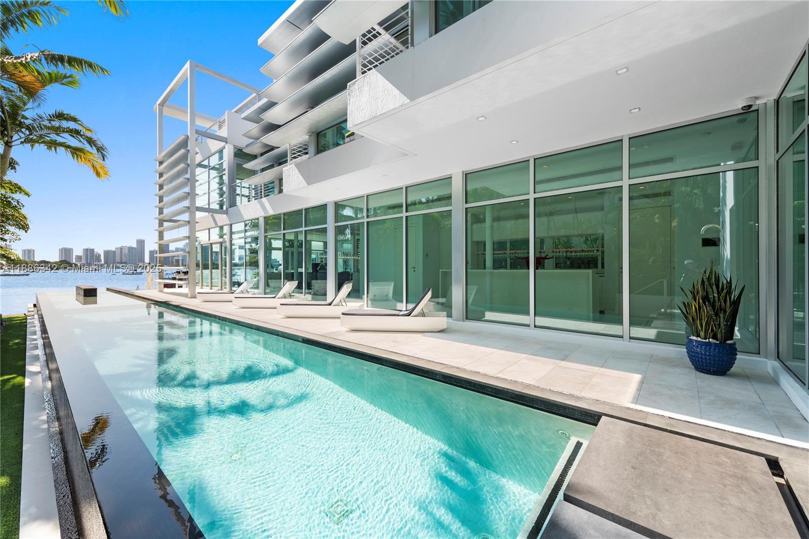 A modern house with a long lap pool, lounge chairs, and floor-to-ceiling glass windows — 440 S Hibiscus Dr, Miami Beach FL 33139, MIAMI BEACH, FL