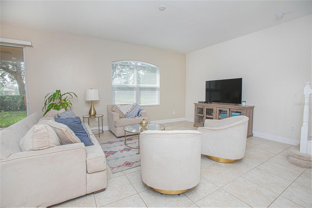 A living room with light tile floors, a sofa, two armchairs, and a dining area — 10665 BELFRY CIRCLE, ORLANDO, FL