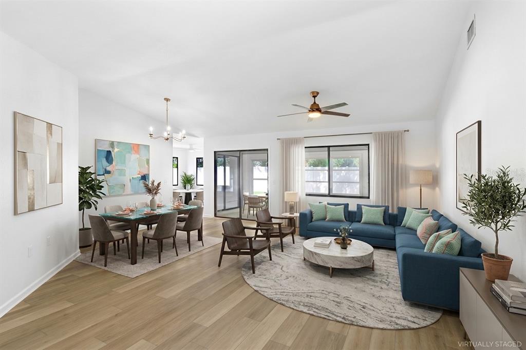 This virtually staged living and dining area features light wood flooring and a blue sectional — 4949 PLEASANT HOLLOW TRAIL UNIT 211, LAKELAND, FL